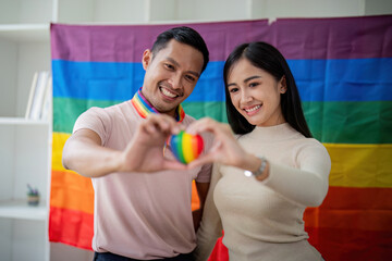 Young gay male and girl friend hands holding rainbow heart with smile face. LGBT, human rights and equality social