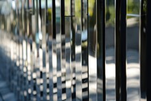  a close up of a metal fence with a building in the back ground and trees on the other side of the fence.