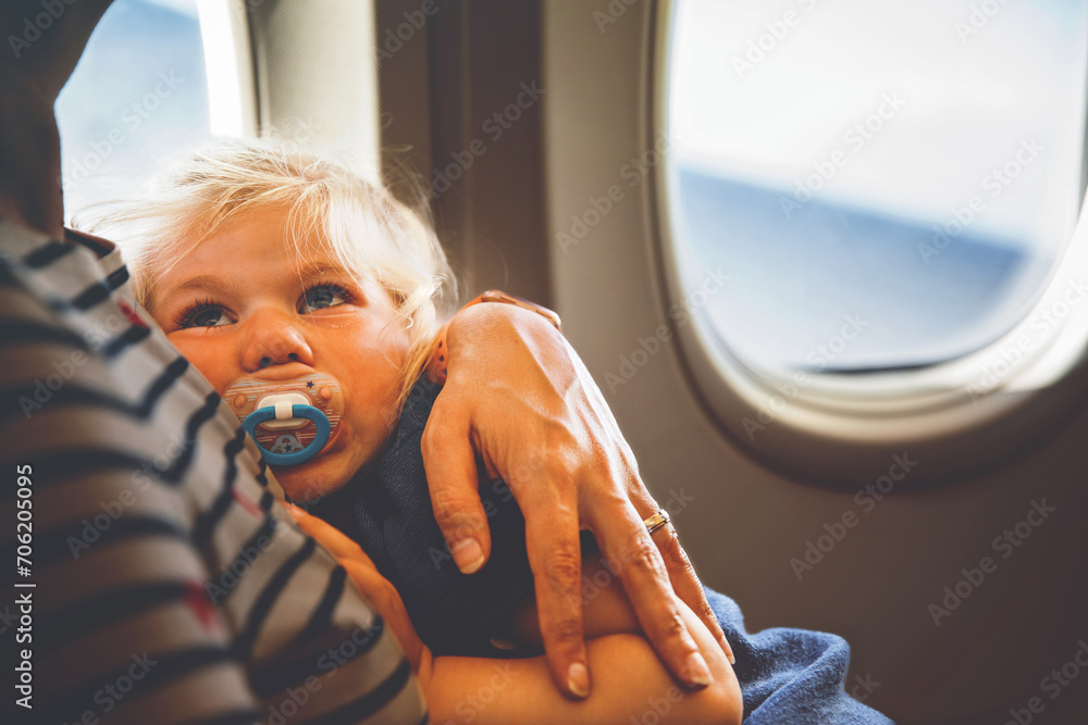 Woman traveling with little child by airplane. Sad tired toddler girl ...