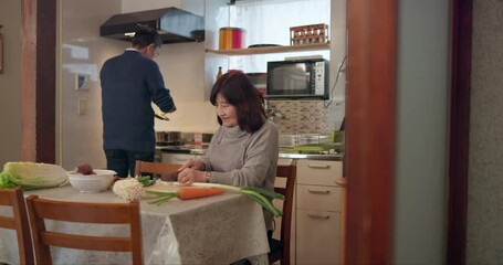 Wall Mural - Japanese couple, kiss and cooking in kitchen in home, cuisine and care together with cutting vegetables. Mature woman, man and supper with romance by nutrition meal, dinner and apartment for soup