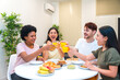 © unai - Multi-ethnic friends toasting with orange juice during breakfast