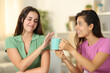 Woman offering coffee cup to a friend who refuses it