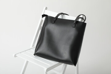 Poster - A black bag on a white chair