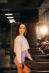 Wall Mural - Young sporty woman running on machine in the gym