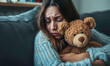 une femme triste tient un ours en peluche contre elle pour se réconforter