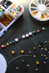 Colorful beads and various jewelry making supplies on dark background. Letter beads spelling I heart DIY. Selective focus.