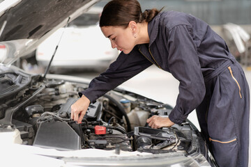 Wall Mural - Auto mechanic in uniform service car engine in workshop garage. Skill female repairman using tool repair maintenance vehicle automobile. Young adult technician working examining in transportation shop