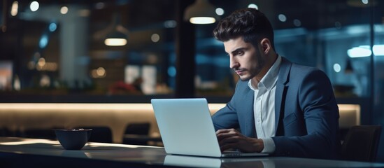 Sticker - Handsome young businessman ponders while working on laptop in office.