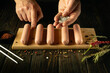 Salt raw meat sausages with the hands of the cook before cooking. Concept for preparing delicious grilled Munich sausages with pepper and rosemary