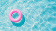 Pink pool float ring floating in a refreshing blue swimming pool. Top view