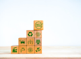 Wall Mural - Net Zero icon and green renewable energy symbol on wooden cube block stack as graph steps isolated on white background. Environmental sustainability, Net zero carbon dioxide reduction concept.