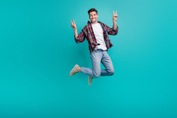 Poster - Full length photo of funny cheerful man dressed plaid shirt jumping high showing two v-signs isolated turquoise color background