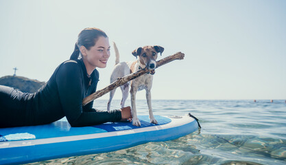 Sea woman sup. Silhouette of happy positive young woman with her dog, surfing on SUP board through calm water surface. Idyllic sunset. Active lifestyle at sea or river. Summer vacation with pets.