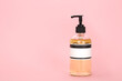 Dispenser for lotion, bath foam or hand soap isolated on a pink background.