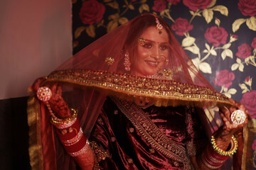 Beautiful portrait of indian bride covering face from dupatta