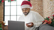 © Krakenimages.com - African american man shopping with laptop and credit card celebrating christmas at home