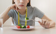 unhappy asian women is on dieting time looking at broccoli on the fork. girl do not want to eat vegetables and dislike taste