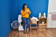 © Krakenimages.com - Young beautiful plus size woman drinking coffee standing at laundry room