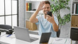 © Krakenimages.com - Hispanic man with beard in a modern office room having a video call on his smartphone, waving at the camera.