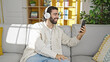 © Krakenimages.com - Young hispanic man having video call sitting on sofa at home