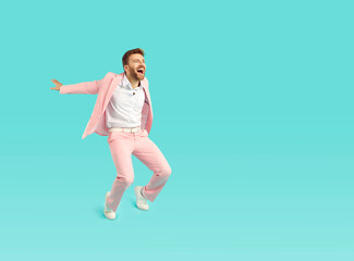 Wall Mural - Happy funny man in stylish pink suit dancing on bright blue color copy space background looking at empty blank copyspace side, asking for attention, screaming, advertising sale, inviting to cool party