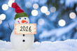 canvas print picture - Winterlicher Willkommensgruß: Schneemann mit Schild, das das Jahr 2026 verkündet, vor einem verträumten Bokeh-Hintergrund