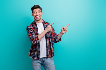 Wall Mural - Photo of excited funky man dressed plaid shirt looking pointing two fingers empty space isolated turquoise blue color background