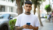 © Krakenimages.com - Cool and tattooed young latin man concentrated on his smartphone, texting while standing outdoors on a sunny city street sporting serious expression and relaxed lifestyle