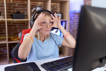 Sticker - Young caucasian woman playing video games wearing headphones trying to open eyes with fingers, sleepy and tired for morning fatigue