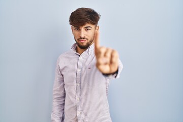 Wall Mural - Arab man with beard standing over blue background pointing with finger up and angry expression, showing no gesture