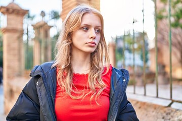 Young blonde woman looking to the side with serious expression at street