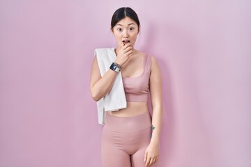 Wall Mural - Chinese young woman wearing sportswear and towel looking fascinated with disbelief, surprise and amazed expression with hands on chin