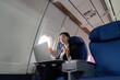 © Natee Meepian - Successful young asian business woman sits in airplane cabin plane and working from anywhere. Flying at first class