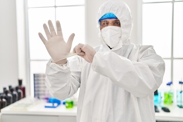 Wall Mural - Young latin man scientist wearing covid protection uniform and gloves at laboratory