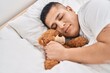 © Krakenimages.com - Young latin man hugging teddy bear lying on bed sleeping at bedroom