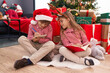 © Krakenimages.com - Brother and sister drawing on notebook sitting on floor by christmas tree at home