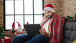 © Krakenimages.com - Young hispanic man watching video on laptop celebrating christmas at home