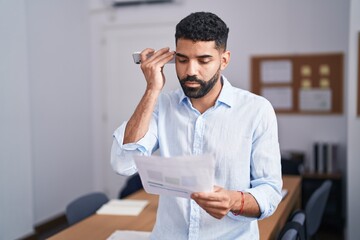 Poster - Young arab man business worker listening voice message by smartphone reading document at office