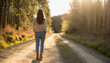 © patpitchaya - A woman walks alone on the dirt road in the woods, relaxing and peaceful moment, generative AI