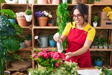 Poster - Young beautiful arab woman florist using diffuser watering plant at flower shop