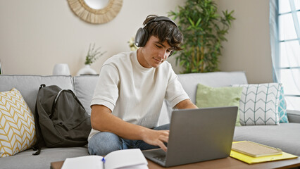 confident young hispanic teenager relaxing, sitting on the sofa in his living room, immersed in stud