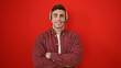 © Krakenimages.com - Smiling young hispanic man, confident call center agent, wearing headset with arms crossed standing over isolated red background, embodying professionalism and efficient customer service.