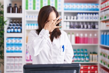 Poster - Middle age brunette woman working at pharmacy drugstore tired rubbing nose and eyes feeling fatigue and headache. stress and frustration concept.