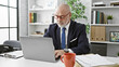 © Krakenimages.com - Senior man with grey beard in glasses working on laptop at office desk