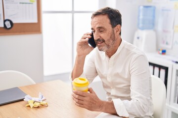 Canvas Print - Middle age man business worker talking on smartphone working at office