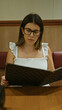 © Krakenimages.com - Beautiful hispanic woman, donning glasses, deeply engrossed in perusing the restaurant menu, navigating her dinner selection in a modern lifestyle dining cafe experience.