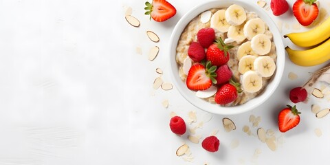 Bowl of oatmeal porridge with strawberry and banana on white table top view. Healthy and diet breakfast.