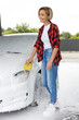 Woman in red shirt cleaning the car at car wash