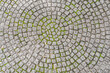 © LRafael - Patio pavers circle design overhead view.Cut square stones in weathered floor with green moss.