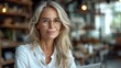 © anatolii - Smiling middle-aged businesswoman in a formal suit sits confidently at the table
